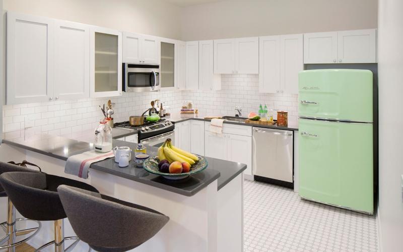 a kitchen with white cabinets and a green fridge
